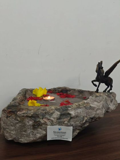 Each natural stone uruli we carve is one of a kind. This piece is shown decorated with floating flowers and a candle, demonstrating its use as a beautiful centerpiece.