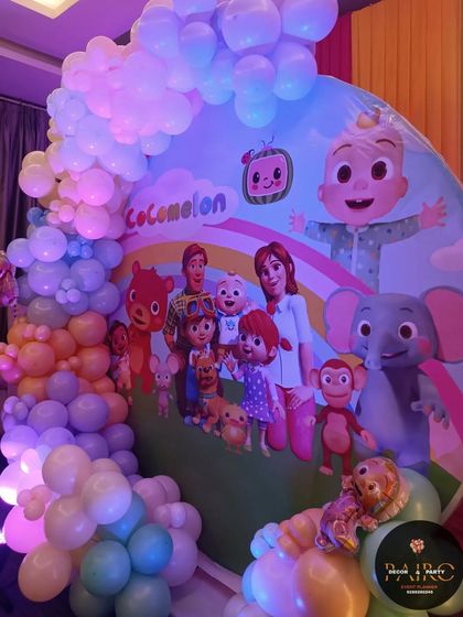 A close-up of a Cocomelon first birthday backdrop. The circular panel is covered with characters, and the pastel balloon arch gives it a soft, dreamy feel.