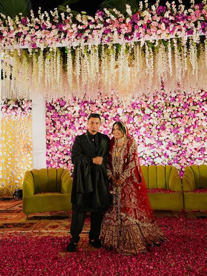 Another stunning shot of the couple on their floral stage. The rich red of the bride's lehenga contrasts beautifully with the pink and purple flowers, making for a vibrant and memorable photo.