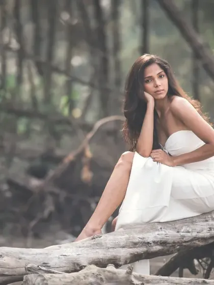 A pensive and beautiful editorial portrait. The natural, woodsy setting and the model's pose create a sense of quiet contemplation.