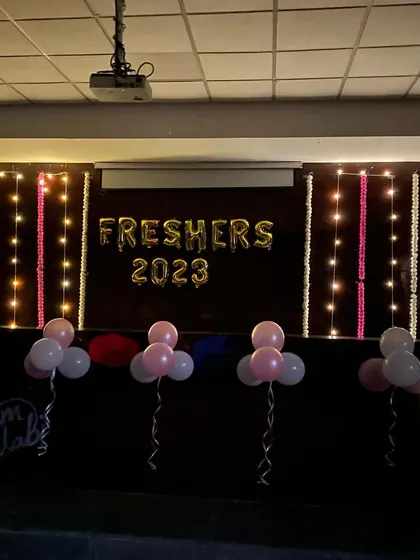A stage decoration for a "Freshers 2023" party, featuring a foil balloon banner and simple balloon bunches.