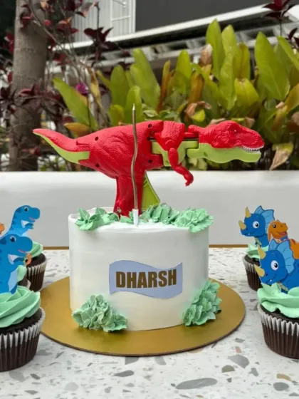This dinosaur themed birthday set was for a huge T-Rex fan. The main cake is a simple, elegant design topped with a toy, surrounded by matching chocolate cupcakes with little dinosaur toppers.