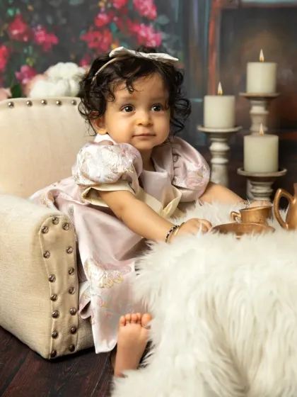 A classic infant portrait with a tea party theme. The soft, fluffy rug and vintage-style props create an elegant and charming scene.