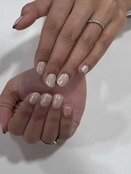 A beautiful unicorn chrome finish on short, neatly shaped nails. This polish gives a pearly, iridescent sheen that looks different from every angle.