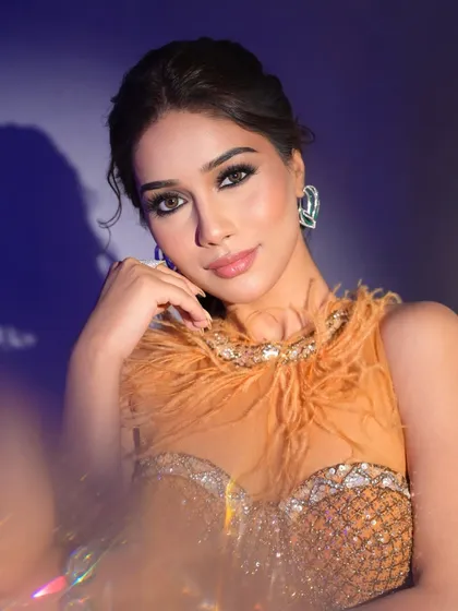 A glamorous shot with dramatic lighting, highlighting the smokey eye and feathered details of the outfit.