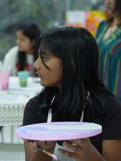 A student holds her work in progress during a painting workshop. Our studio is a place to de-stress, recharge, and connect with your creative side, no matter your skill level.