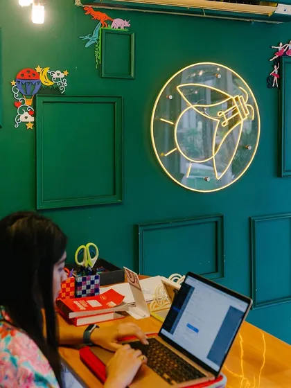 A quiet corner of our studio, ready for the next wave of creativity. The green wall and neon light create a vibrant yet calming atmosphere for your art session.