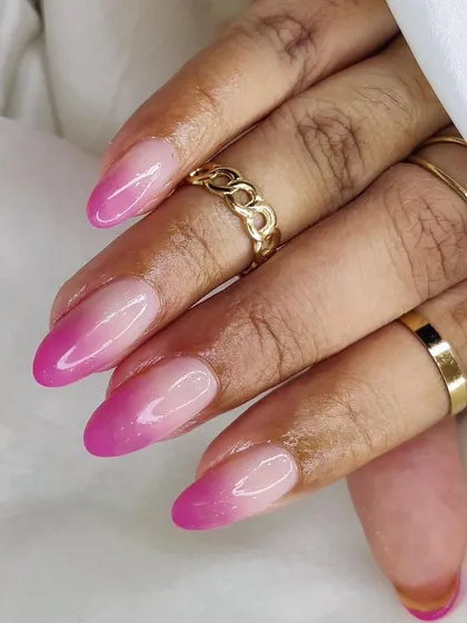 A vibrant pink ombré manicure, showing the smooth transition from a natural base to a bright pink tip.