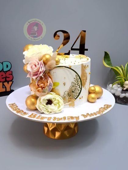 An aesthetic floral cake for a 24th birthday, featuring a white and gold design with beautiful sugar flowers.