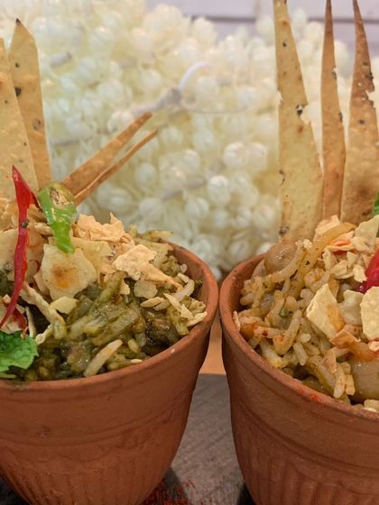 A modern take on bhel puri or a similar savoury rice dish, served in individual terracotta cups and topped with crispy crackers for texture.
