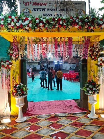 A grand entrance arch for a Haldi ceremony. The yellow structure is decorated with red and white flowers and hanging wisteria, creating a stunning welcome for guests.