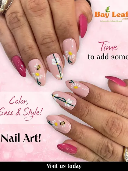 See the detail in our custom nail art. This design features a soft pink base with delicate white daisy art, complete with tiny bees and vibrant magenta accent nails for a cheerful, stylish look.