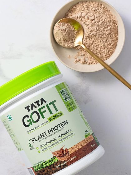 A top-down shot of the Tata GoFit tub with a bowl of protein powder, styled with a simple white background to emphasize the product's clean, no-fuss nature.