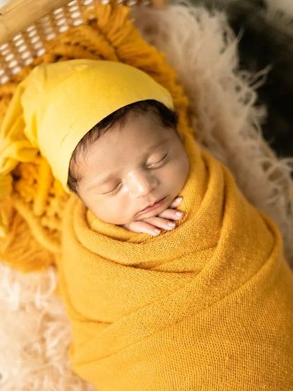 All wrapped up and cozy in a warm yellow swaddle. This classic wrapped pose is perfect for keeping the baby comfortable and secure while we capture their peaceful sleep.