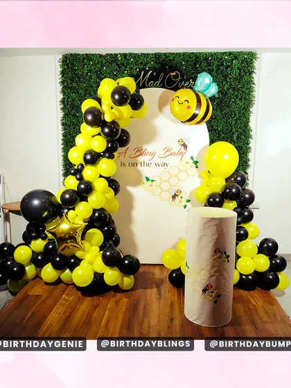 A "Bling Baby is on the way" baby shower with a fun bee theme. The black and yellow balloon arch and honeycomb-patterned backdrop are perfect for celebrating the mom-to-be.