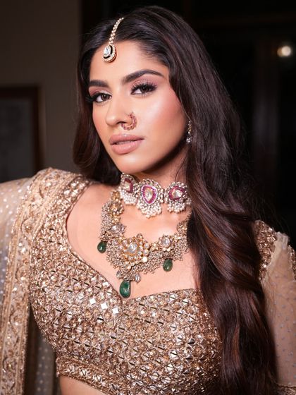 A close-up on the intricate jewelry. The layered choker with emerald and ruby drops adds a pop of color to the monochrome golden look.