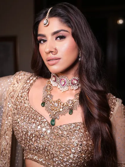 A close-up on the stunning jewelry. I paired this golden lehenga with a unique choker featuring pink and green stones for a pop of color.