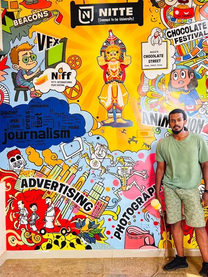 A proud moment with the finished doodle art at Nitte Institute of Communication. The wall is a visual explosion of themes relevant to the students, from filmmaking and advertising to a central figure of a Yakshagana performer.
