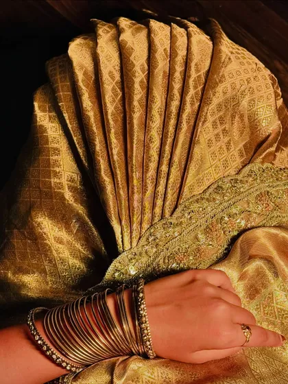 The beauty of a saree is in its details. This is a close-up of perfectly set pleats on a golden silk saree, a fundamental skill I focus on. Achieving this level of precision is what elevates a simple drape to a work of art.