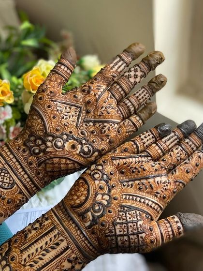 A beautiful shot of both palms, covered in a dense and traditional bridal mehendi pattern.