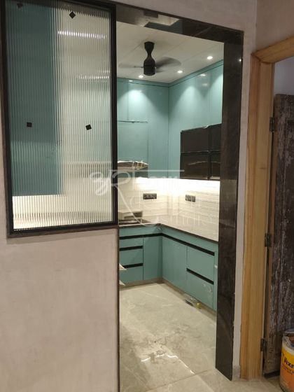 A view from the entrance, showing how the kitchen seamlessly integrates with the rest of the home. The fluted glass partition provides a sense of openness while subtly separating the spaces.