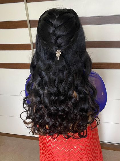 A simple half-updo with a small braid and bouncy curls, secured with a single pearl clip.