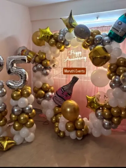 Celebrating a silver anniversary in style. This elegant setup for a 25th anniversary features a beautiful balloon arrangement in gold, silver, and white, complete with large number balloons and champagne bottle props to mark the special milestone.