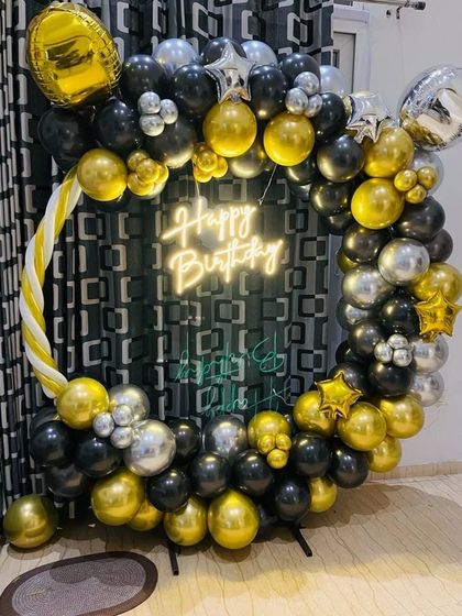 A classic black, gold, and silver balloon ring. This decoration includes a neon sign and is perfect for creating a stylish photo corner at any adult birthday party.