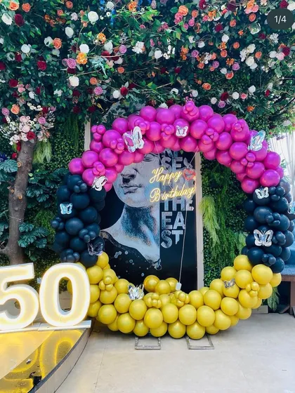 A unique and artistic setup for a 50th birthday, with a multi-colored balloon ring and a modern art backdrop.