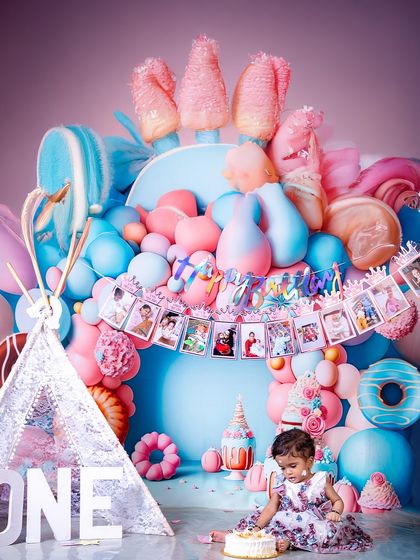 A sweet and candid moment of the birthday girl exploring her cake. The colorful, candy-themed setup creates a vibrant and joyful atmosphere for this first birthday milestone.