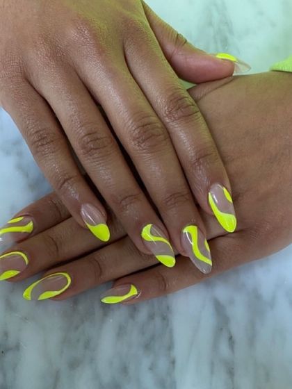 Nail inspiration showing a bold and graphic look with neon yellow abstract lines on a sheer base.
