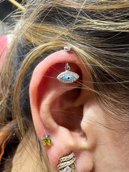 An evil eye hanging paired with a green peridot stud for a pop of color and protection.