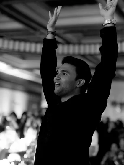 A candid black and white portrait capturing the groom's pure joy and energy during his sangeet performance.
