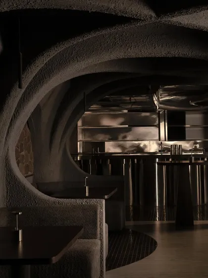 The interior of Call Me Ten, where organic, cave-like forms in textured concrete create intimate dining pods. The design is a dialogue between raw materiality and refined form, crafting a unique, subterranean atmosphere for this Japanese-inspired restaurant.