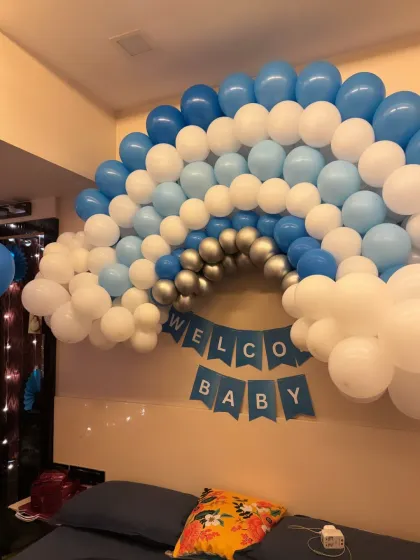 A simple yet beautiful rainbow-shaped balloon arch for a 'Welcome Baby' wall decoration. This is a great option for smaller spaces or for decorating the wall above a bed or sofa.