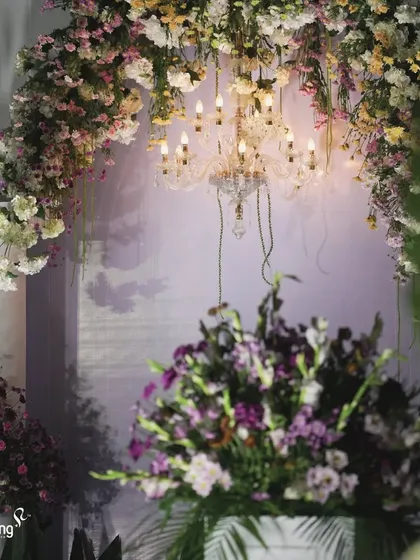 A close-up of the floral decor, showing the rich combination of purple and white flowers, complemented by the warm glow of a chandelier.
