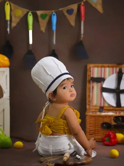 A curious glance from our little chef. Sitter sessions, usually around 6-8 months, are perfect for capturing these adorable expressions as babies can sit up but aren't on the move yet.