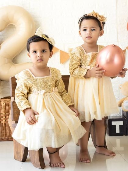 The two sisters together, one holding a balloon. Capturing the dynamic between siblings, especially twins, is a special part of these sessions.