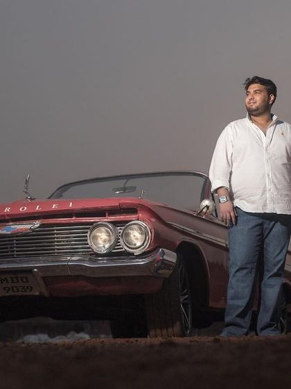 A moody and atmospheric shot of the couple with a vintage car at dusk, creating a romantic and dramatic pre-wedding portrait.