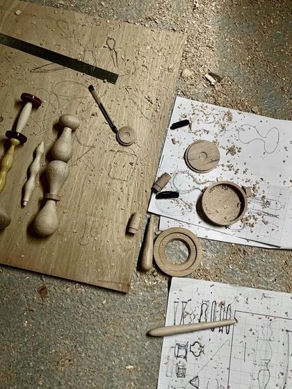 From sketch to reality. Our design drawings lie on the workshop floor next to the first physical prototypes of the Channapatna modules, illustrating the journey from a concept to a tangible, handcrafted object.