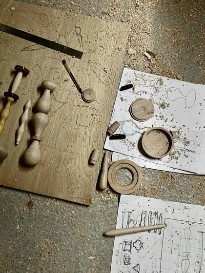 From sketch to reality. Our design drawings lie on the workshop floor next to the first physical prototypes of the Channapatna modules, illustrating the journey from a concept to a tangible, handcrafted object.