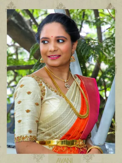 A simple yet elegant off-white blouse with minimal butti embroidery. This versatile piece is paired with a vibrant orange and pink saree for a classic look.