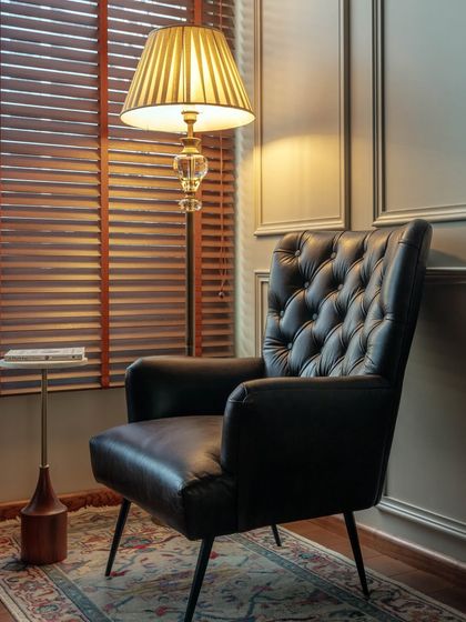 This reading nook within the office features a comfortable tufted leather armchair and a classic floor lamp. It’s a perfect example of how I like to incorporate residential-style comfort into a commercial setting, making the space feel more welcoming.