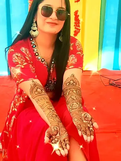 A happy bride showing off her symbolic and intricate bridal henna.