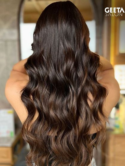 Long, dark hair with a subtle balayage, adding dimension and movement to the waves.