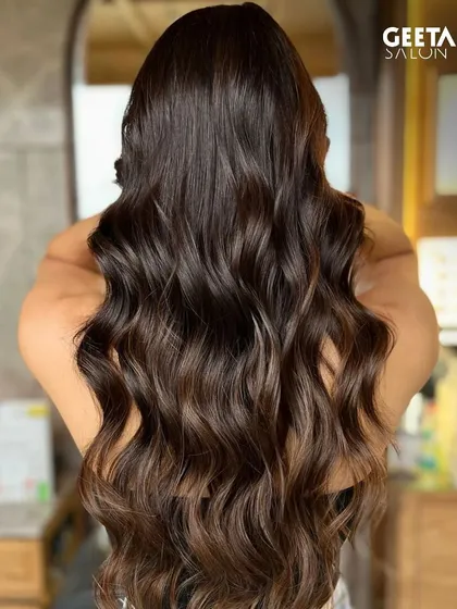 Long, dark hair with a subtle balayage, adding dimension and movement to the waves.
