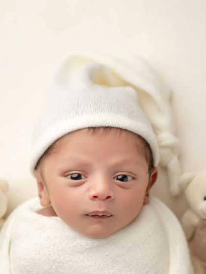 Wide-eyed and wonderful. This little one is alert and taking in the world, surrounded by a lineup of his first teddy bear friends.