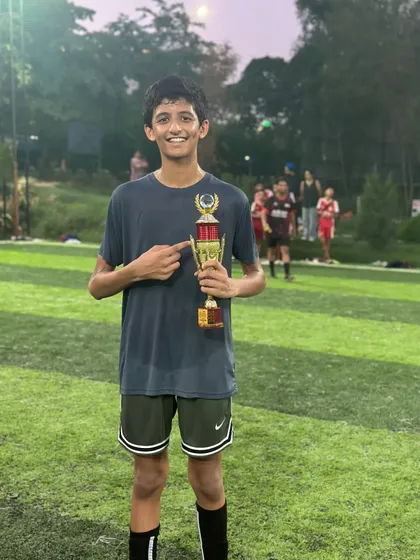 This player proudly points to his trophy, a symbol of his dedication and skill on the field.