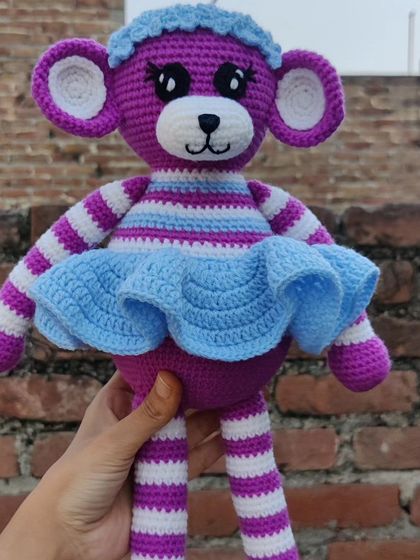 Holding up the full-length monkey doll to show its size and striped details.