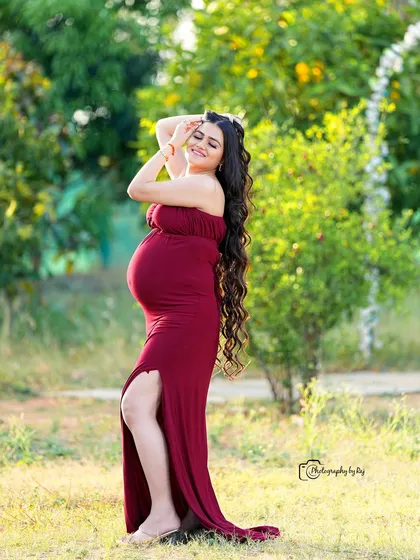 A radiant mother-to-be in a simple yet elegant red fabric wrap, enjoying the sunshine in our private garden.